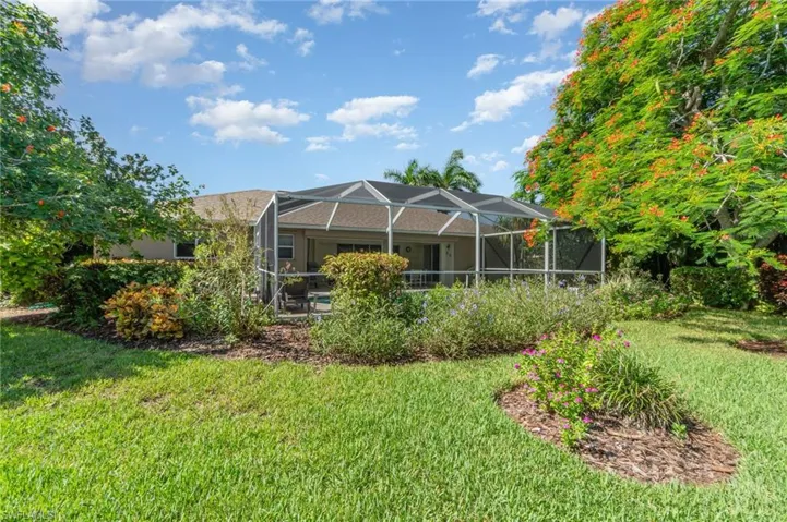 Rear view of property with a sunroom, a lanai, a lawn, and a patio area