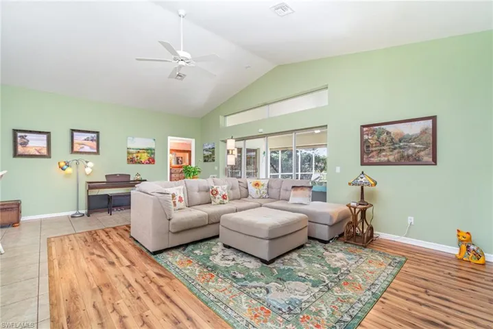 Living area with high vaulted ceiling, a ceiling fan, and light wood-style flooring