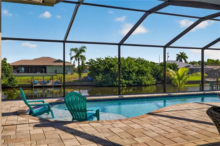 Screened-in pool area featuring a paver patio and integrated spa