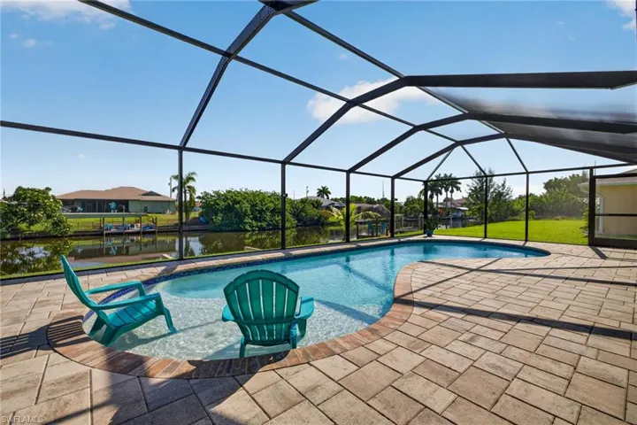 Screened lanai featuring a freeform swimming pool with a sun shelf