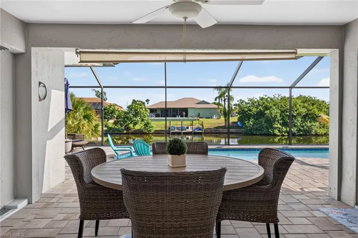 Screened lanai featuring a ceiling fan, patterned tile flooring, and direct access to a private swimming pool and canal frontage