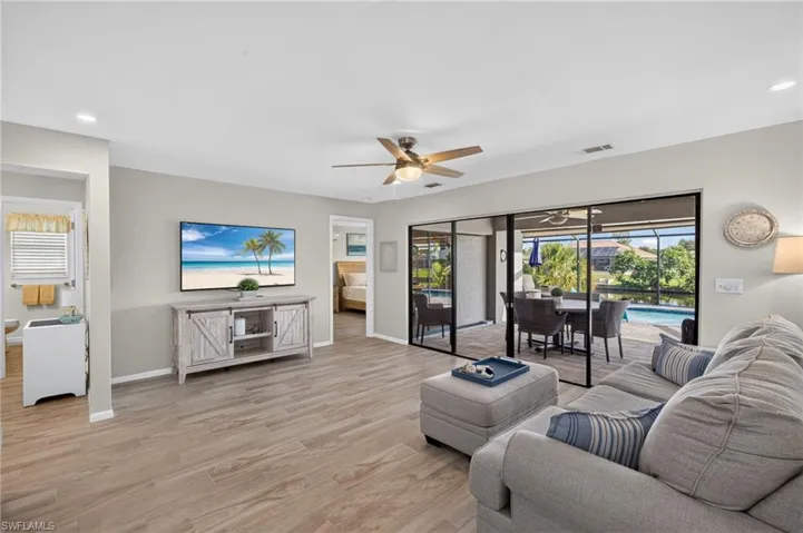 Spacious living area featuring light ceramic plank tile flooring, a contemporary ceiling fan, recessed lighting, and a neutral wall palette