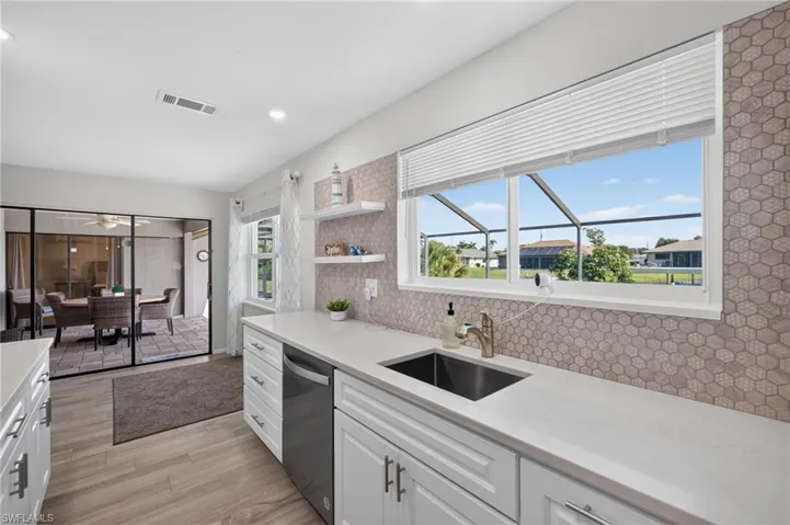 Modern kitchen featuring white cabinetry, light-toned countertops, and a hexagonal tile backsplash