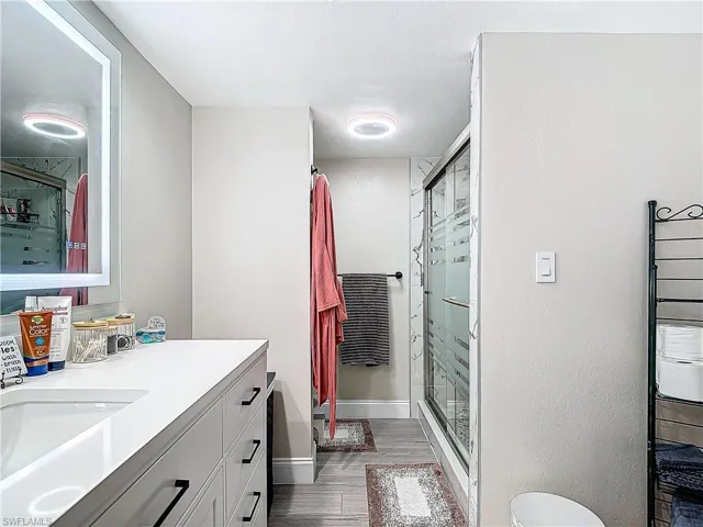 Full bath featuring a stall shower, quartz vanity and Bluetooth fan