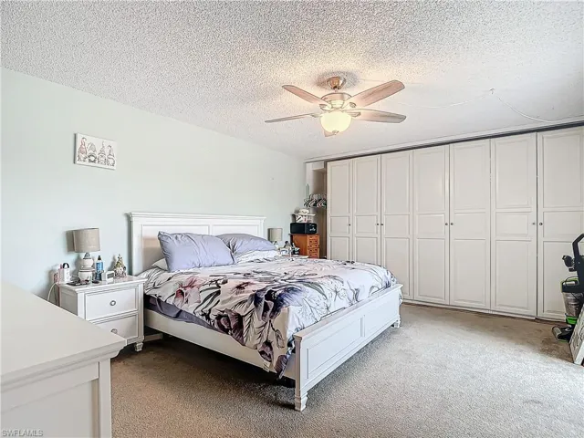 Bedroom featuring light colored carpet, ceiling fan, and a textured ceiling