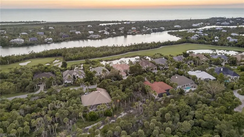 Aerial view of property and surrounding area with nearby suburban area, a large body of water, and a golf club