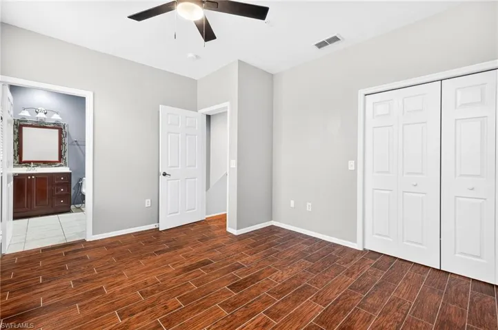 Unfurnished bedroom with ceiling fan, wood tiled floors, a closet, and ensuite bathroom