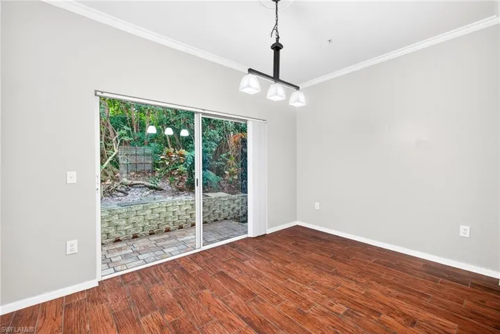 Unfurnished dining area with ornamental molding and dark wood-type flooring