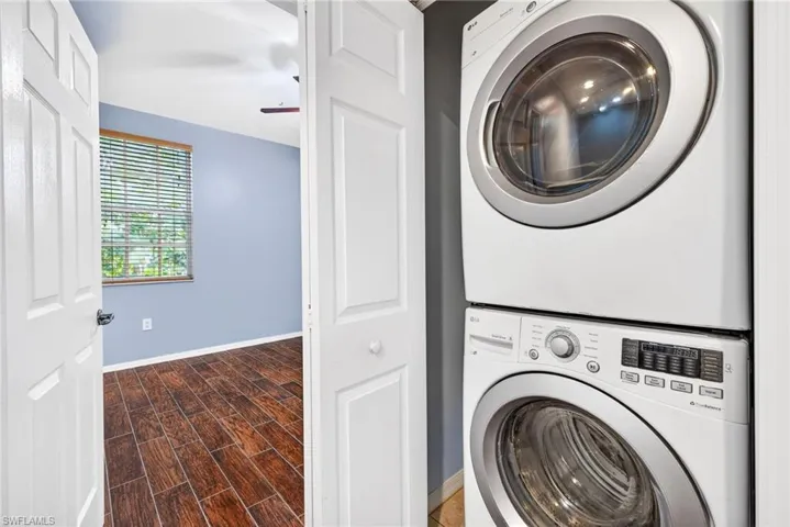 Laundry room with stacked washer and clothes dryer, wood finish floors, and a ceiling fan
