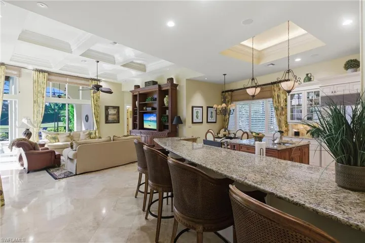 Kitchen with light stone counters, decorative light fixtures, a kitchen island, a breakfast bar, and ornamental molding