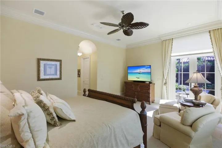 Carpeted bedroom with access to exterior, arched walkways, ornamental molding, and ceiling fan