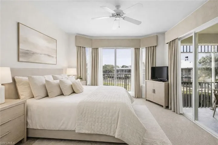 Virtual staged bedroom featuring access to exterior, light carpet, and ceiling fan