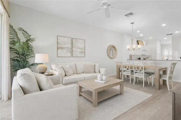 Virtual staged living area featuring a ceiling fan, light wood-style flooring, and suspended lighting