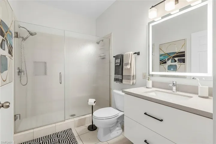 Virtual staged full bath with vanity, a stall shower, and light tile patterned floors