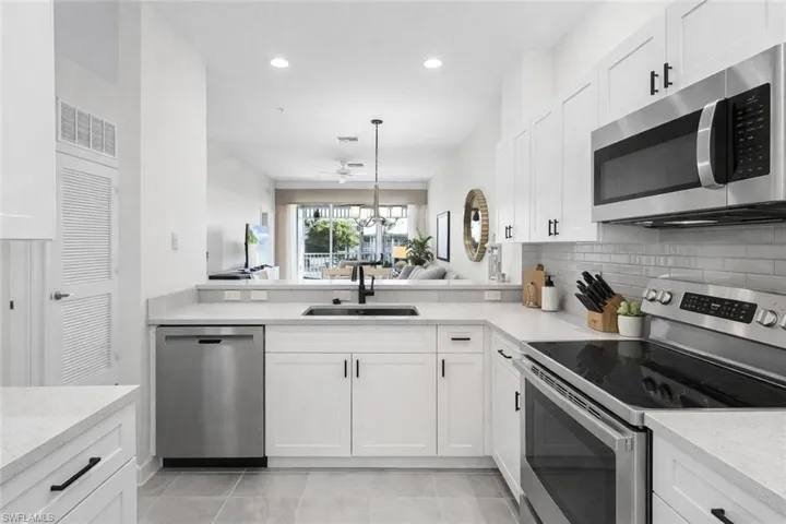 Virtual staged kitchen featuring stainless steel appliances, white cabinetry, light stone counters, and tasteful backsplash