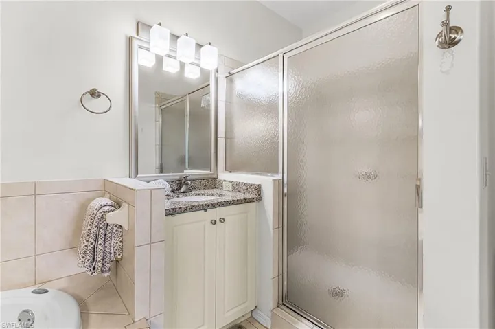 Full bathroom with vanity, a shower stall, a bath, and tile walls