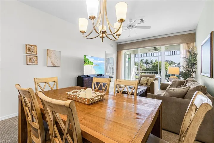 Carpeted dining space with a chandelier and a ceiling fan