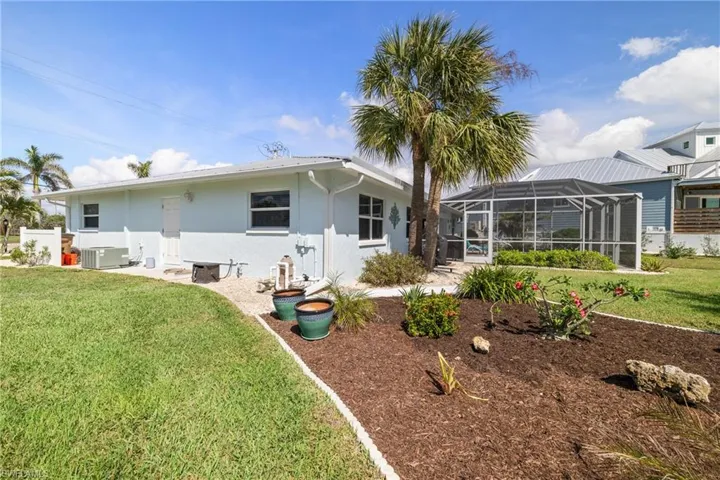 Rear view of house featuring a lawn, cooling unit, and glass enclosure