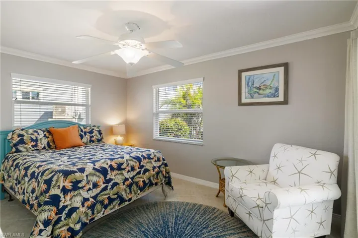 Tiled bedroom with ceiling fan, crown molding, and multiple windows