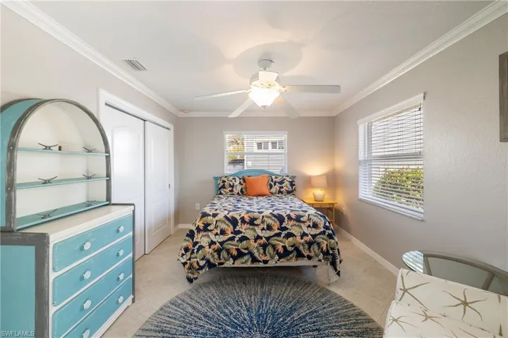 Bedroom with ceiling fan, light tile patterned floors, crown molding, and a closet
