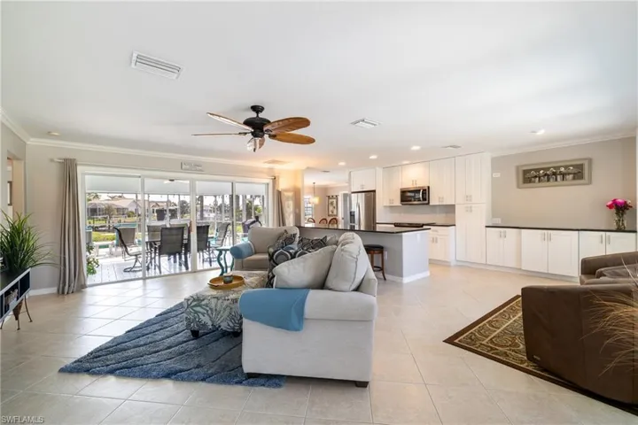 Tiled living room with crown molding and ceiling fan