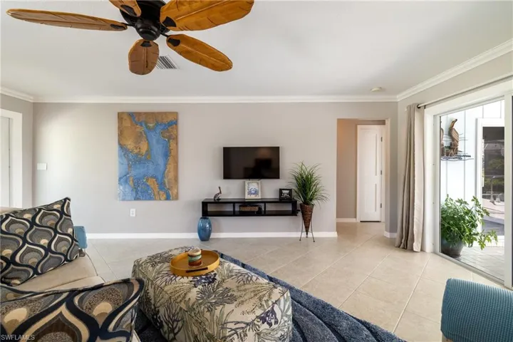 Tiled living room featuring ornamental molding and ceiling fan