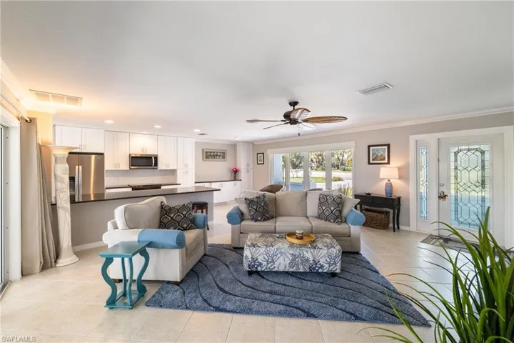 Living room featuring light tile patterned floors, ceiling fan, and ornamental molding