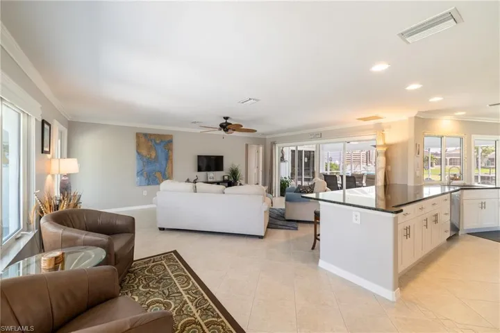 Kitchen with stainless steel dishwasher, light tile patterned floors, white cabinetry, and a wealth of natural light