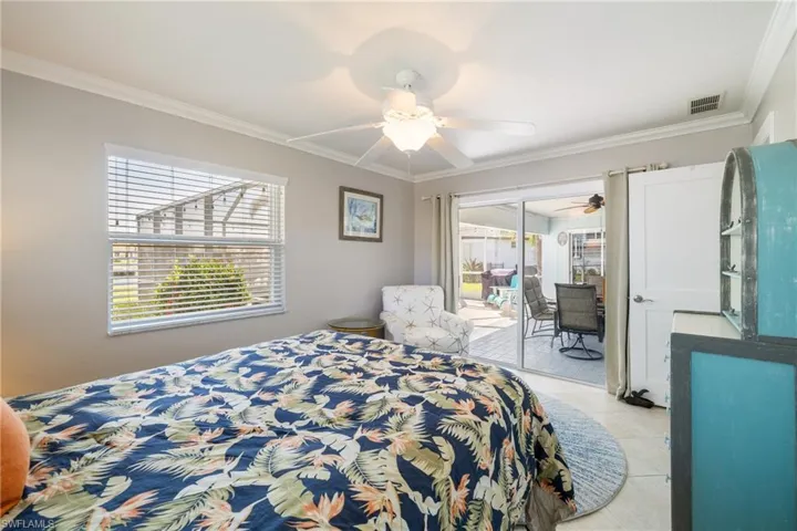 Bedroom featuring access to exterior, crown molding, light tile patterned flooring, and ceiling fan