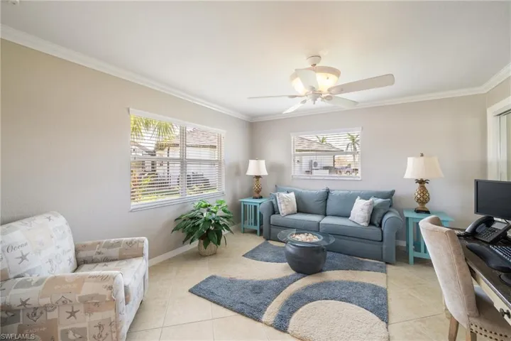 Tiled living room with ceiling fan and ornamental molding