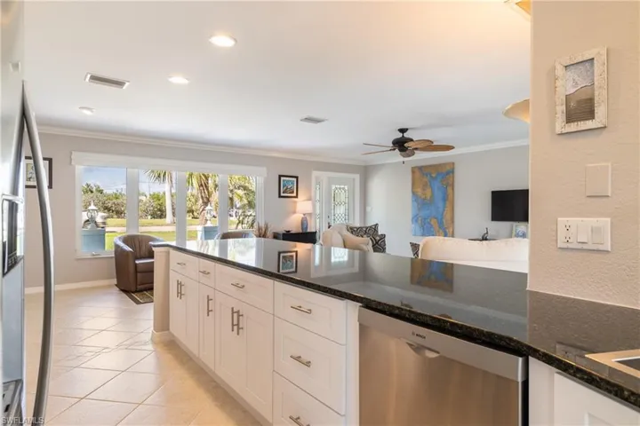 Kitchen featuring stainless steel appliances, light tile patterned floors, dark stone counters, white cabinets, and crown molding