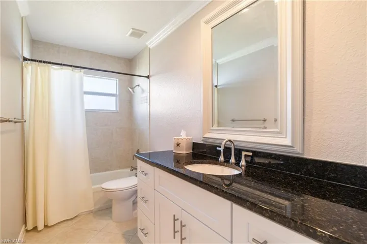 Full bathroom with shower / bath combo with shower curtain, vanity, tile patterned flooring, toilet, and ornamental molding