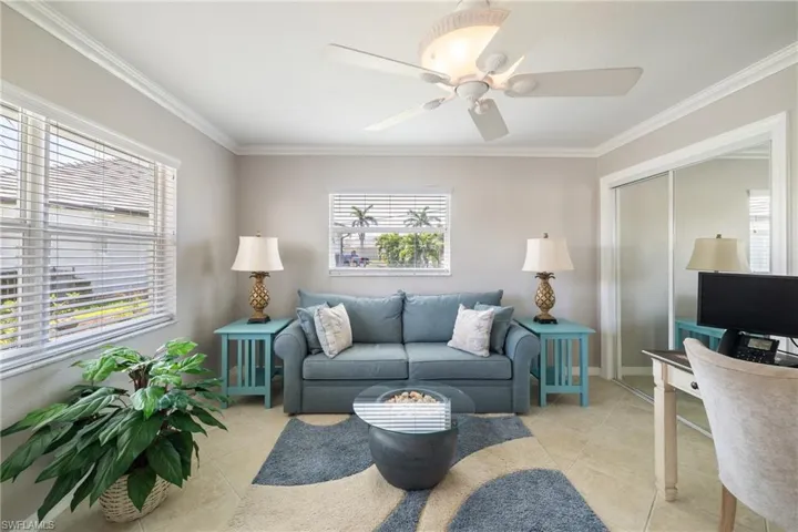 Living room featuring a wealth of natural light, crown molding, and light tile patterned floors