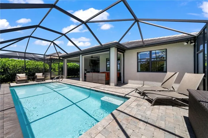 View of pool with a patio, ceiling fan, and glass enclosure