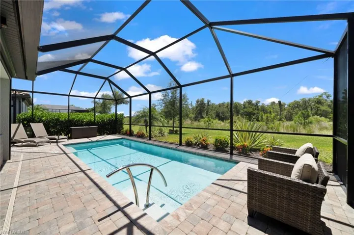 View of pool featuring glass enclosure and a patio area