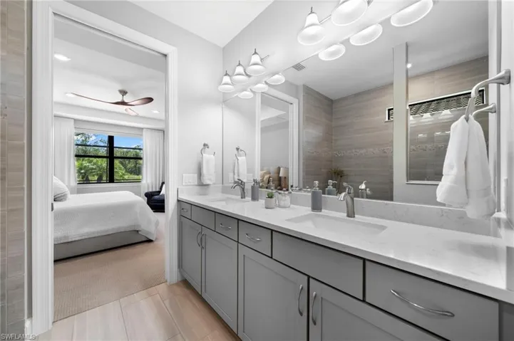 Bathroom featuring ceiling fan, double sink vanity, and tile patterned flooring