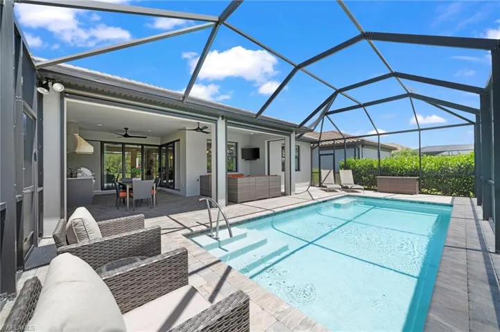 View of pool featuring a lanai, a patio area, an outdoor living space, and ceiling fan