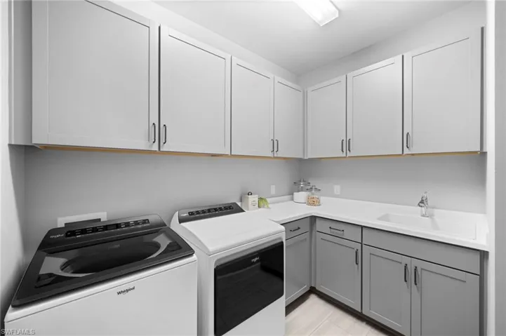 Clothes washing area with separate washer and dryer, cabinets, and sink