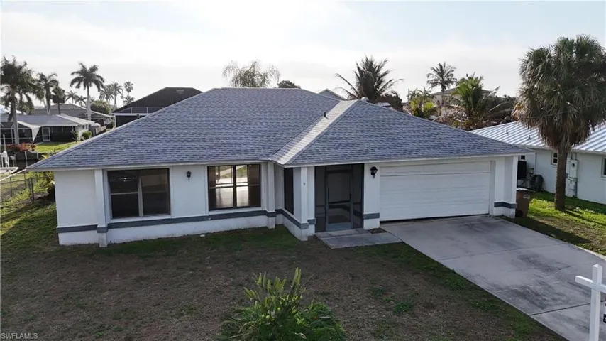 Ranch-style house with a shingled roof, driveway, an attached garage, stucco siding, and a front lawn