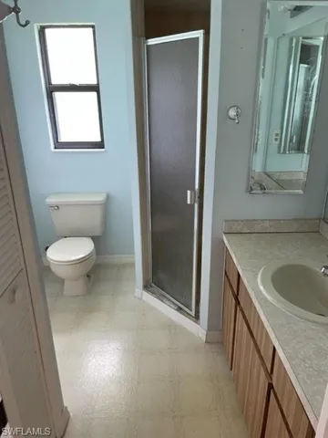 Full bathroom featuring vanity, a stall shower, light flooring, and a closet