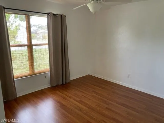 Spare room with dark wood-type flooring and a ceiling fan