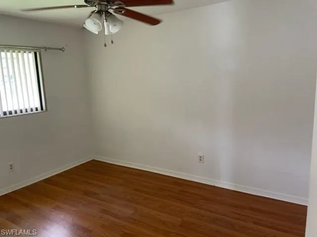 Unfurnished room featuring a ceiling fan and dark wood-type flooring
