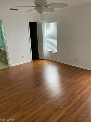 Unfurnished bedroom featuring light wood-style flooring, ceiling fan, a closet, and ensuite bath