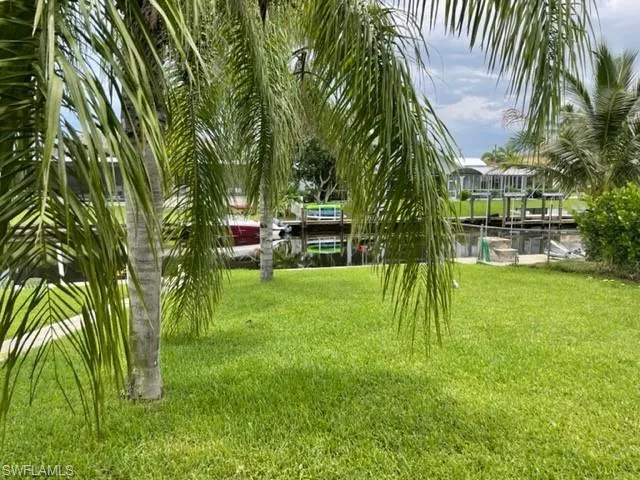 View of grassy yard featuring a water view, boat lift, and a boat dock