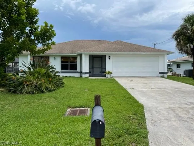 Ranch-style house with driveway, a front yard, stucco siding, and a garage