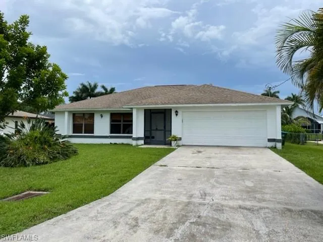 Ranch-style home featuring driveway, stucco siding, a front lawn, and an attached garage