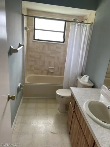 Full bath featuring vanity, shower / bathtub combination with curtain, and light floors