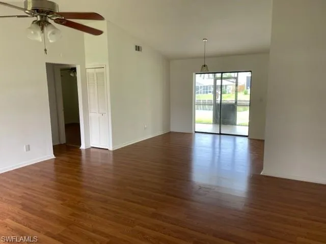 Unfurnished room featuring dark wood-type flooring, a ceiling fan, and high vaulted ceiling