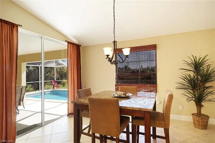 Dining space featuring light tile patterned floors, vaulted ceiling, and a notable chandelier