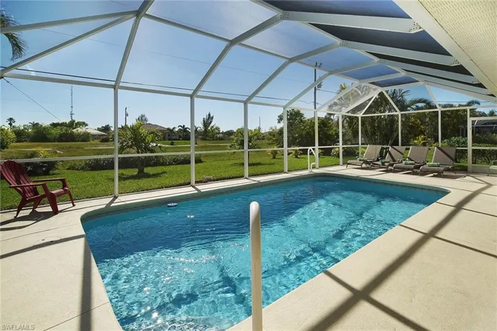 Pool with a patio area, a lawn, and glass enclosure